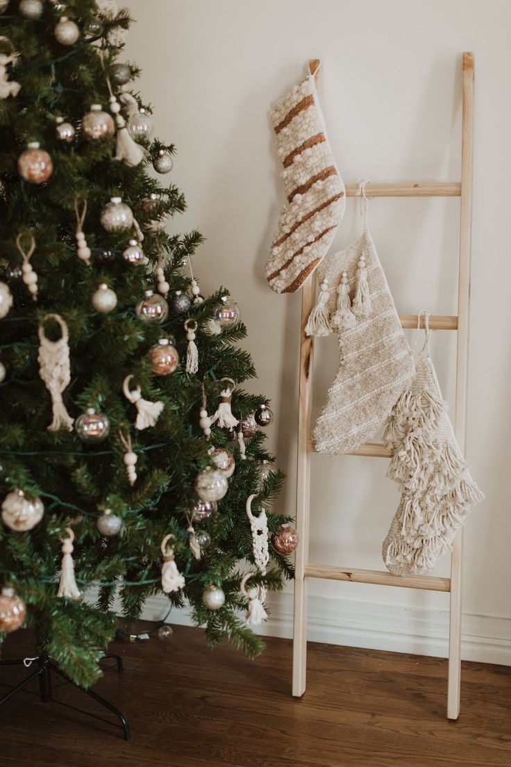 a ladder next to a christmas tree with ornaments on it and a blanket hanging from the top