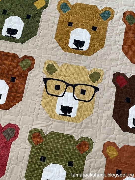 a quilt with bears wearing glasses on it