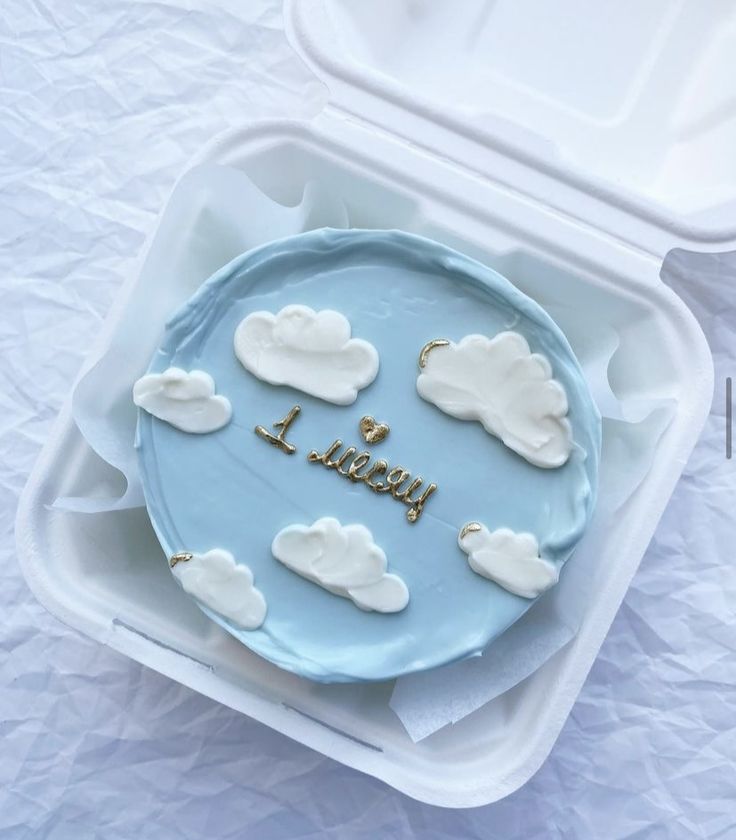 a blue cake with white clouds and the words i love you written on it in gold letters