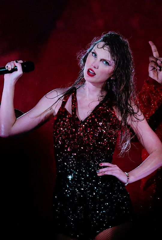 a woman in a sequined dress holding a microphone and making the peace sign