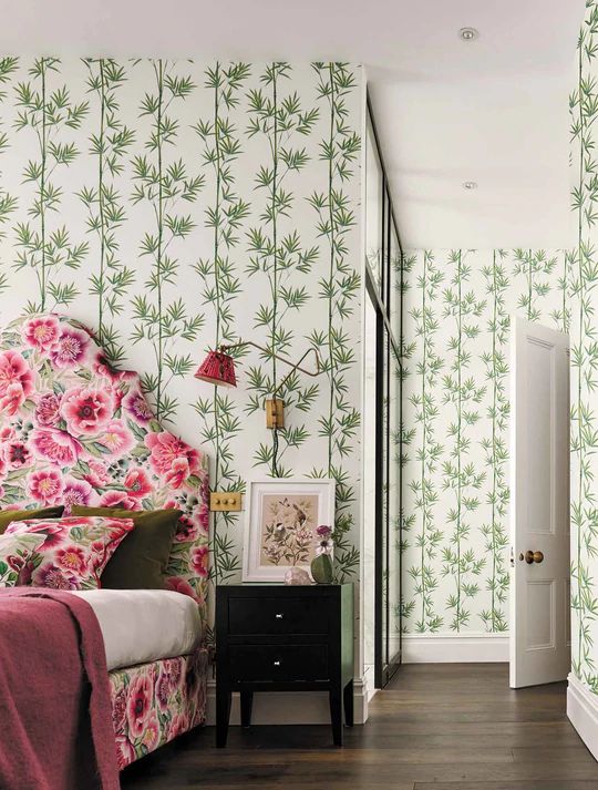 a bedroom with floral wallpaper and pink bedding