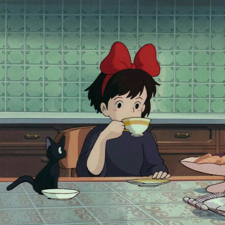 two people sitting at a table with cups and plates in front of them, one holding a cat