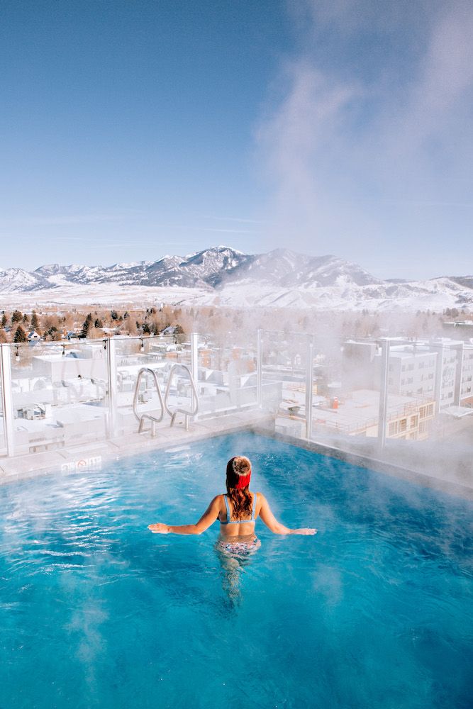 a woman in a hot tub on top of a snow covered mountain