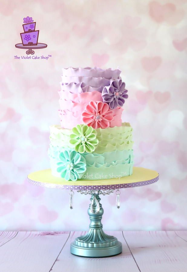 there is a multi layer cake with flowers on the top and bottom tier, sitting on a stand