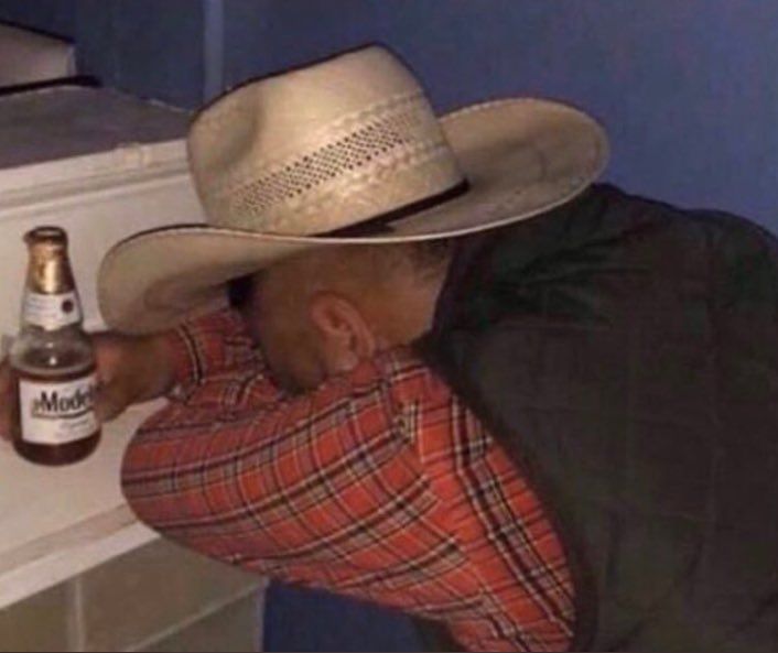 a man wearing a cowboy hat leaning against a counter with a beer in his hand