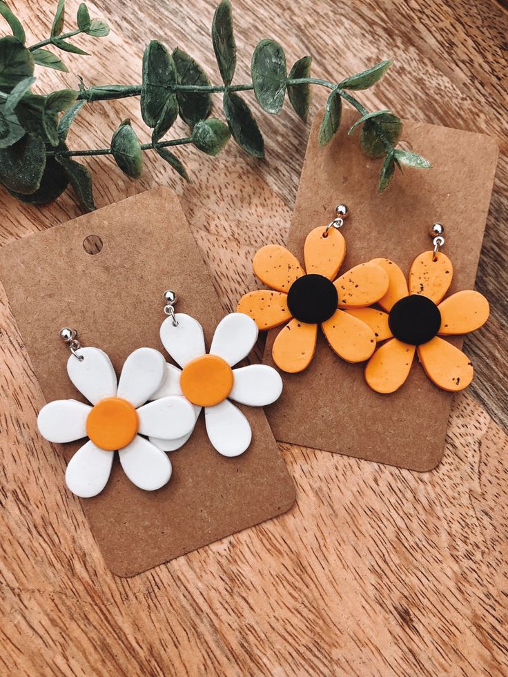 three yellow and white flower earrings sitting on top of a wooden table