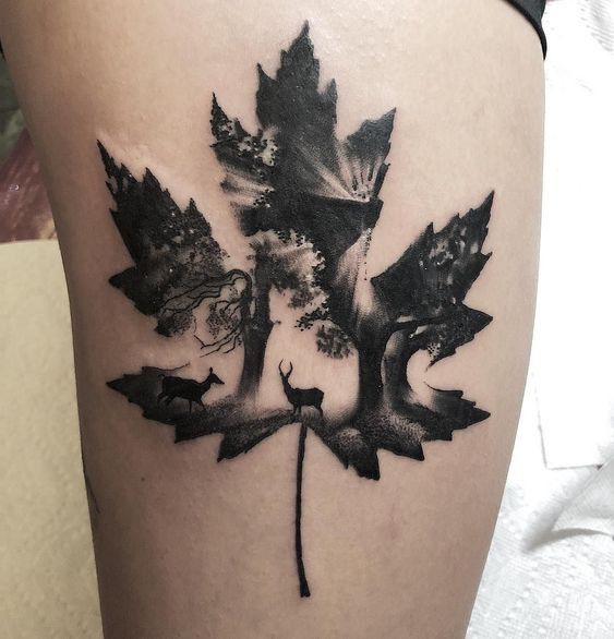 a black and white photo of a maple leaf tattoo on the side of a woman's thigh