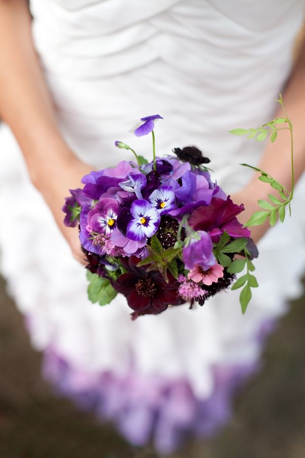 a bride holding a bouquet of purple flowers