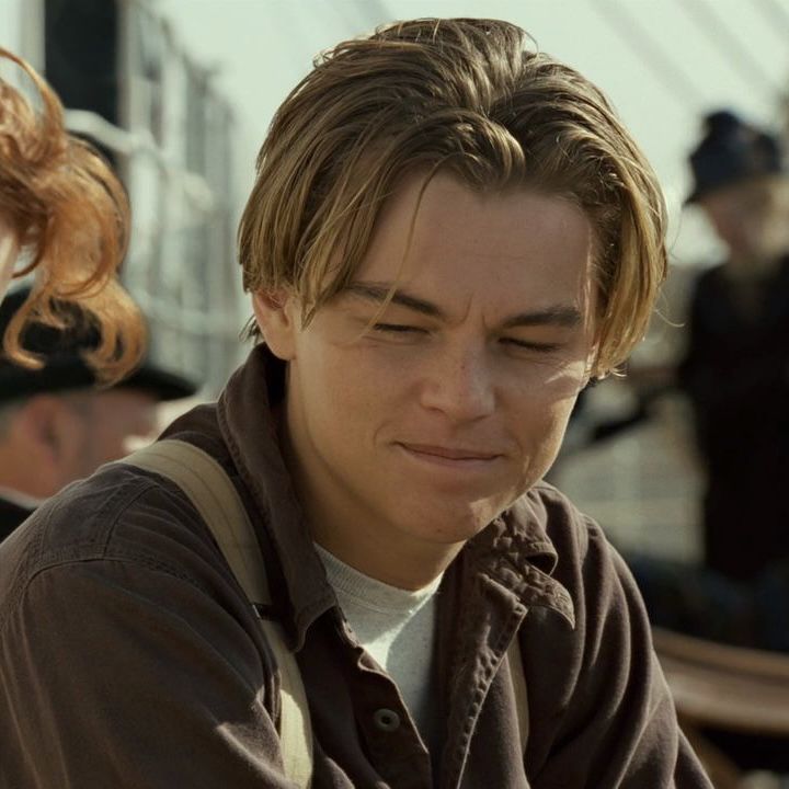 a young man is looking down at his cell phone while on the deck of a ship