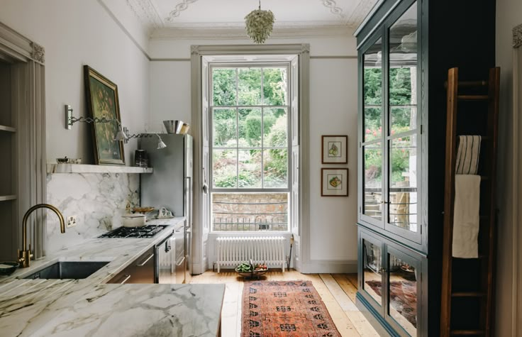 a kitchen with marble counter tops and an area rug in front of a window that leads to the outside