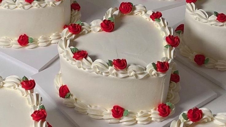 several heart shaped cakes with red roses on the top and bottom, all decorated in white frosting