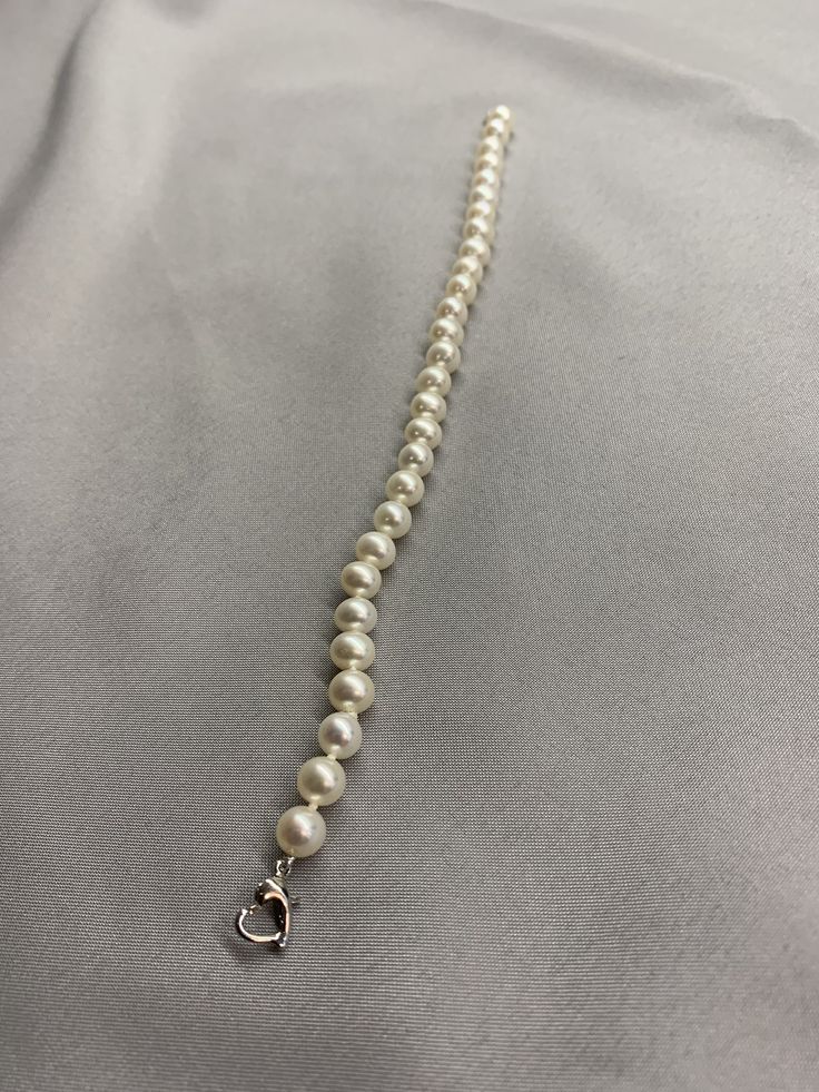 White Freshwater Pearl Bracelet. This bracelet features 28 White Freshwater Pearls AAA round to near round high luster 6.2mm with a heart clasp that is 18K white gold plate over 925 silver. The bracelet is 7 1/2 inches long measured laying flat. I hand knotted this bracelet using spectra thread. I use it instead of silk for my freshwater pearls. It does not stretch, hold oils, or break easily. It can also be gotten wet. I also like the heart clasp, they are easier to connect. We guarantee all of Elegant Sterling Silver Bracelet With Clasp For Gift, Single Strand Sterling Silver Bracelet, Sterling Silver Single Strand Bracelet, Classic Jewelry With Extender, Elegant Sterling Silver Bracelet With Clasp, Classic Jewelry With Extender For Formal Occasions, Classic Beaded Bracelets With Sterling Silver Clasp As Gift, Classic Sterling Silver Bracelet With Extender, Elegant Pearl Bracelet With Lobster Clasp And Round Beads