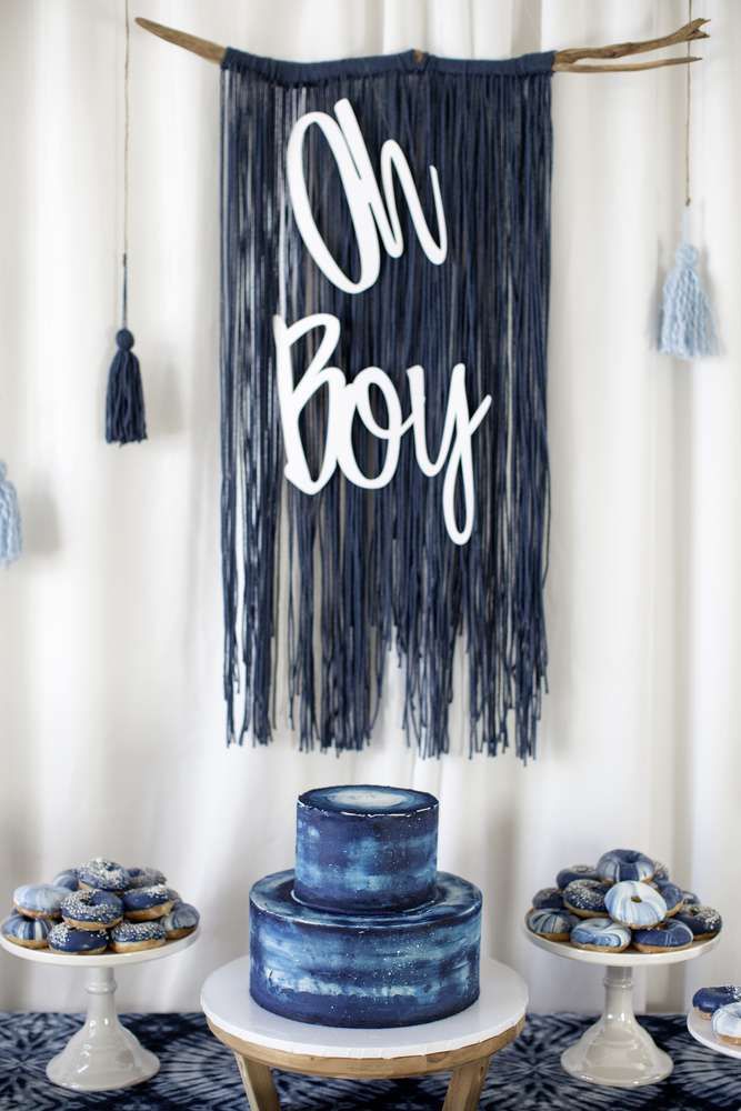 a table topped with blue cakes and tassels next to a sign that says oh boy