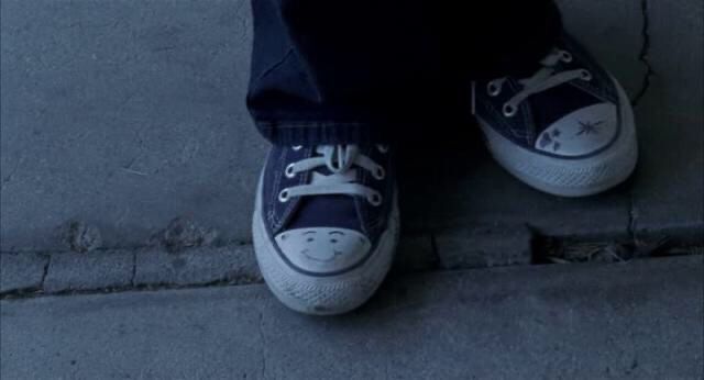 a person standing on the sidewalk wearing blue sneakers