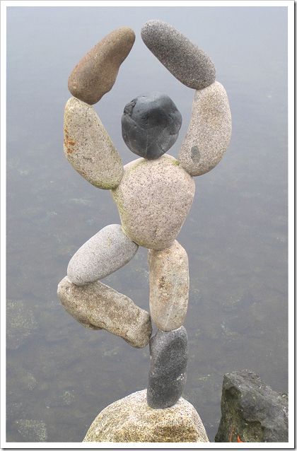 a statue made out of rocks sitting on top of a rock in the middle of water