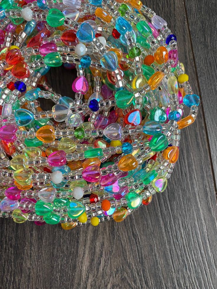 a bunch of colorful beads sitting on top of a wooden table