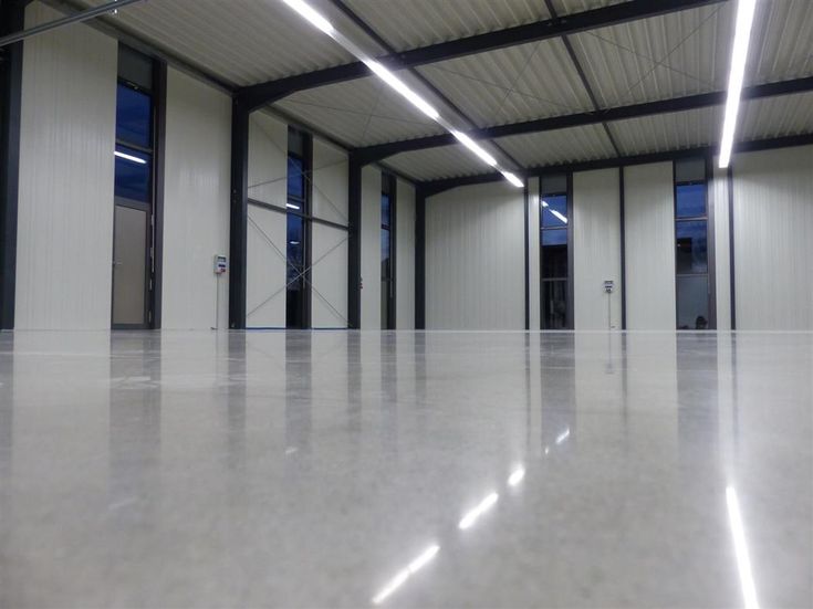 an empty warehouse with white walls and windows, in the middle of a large floor