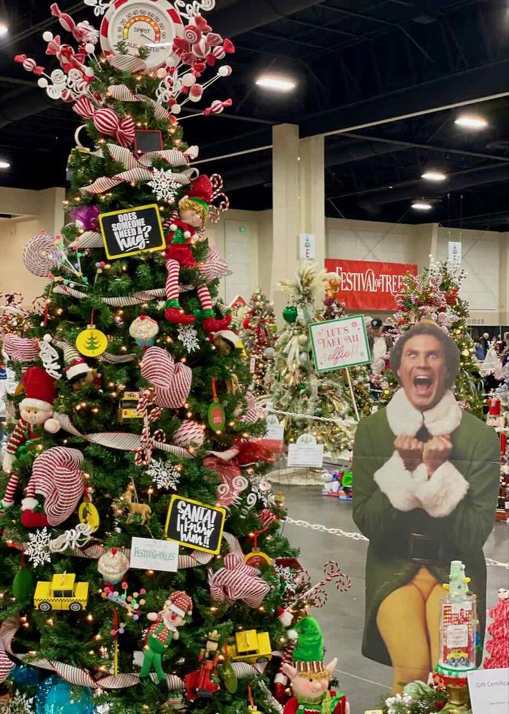 a christmas tree is decorated with ornaments and signs for the holiday season in a store