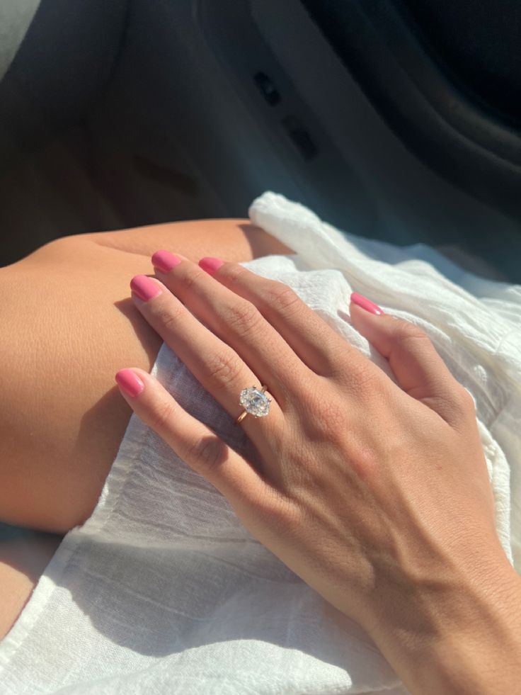 a woman's hand on the arm of her car seat, with a diamond ring