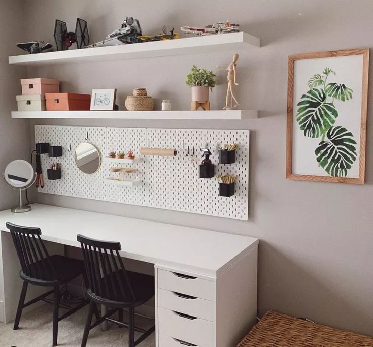 a white desk with two black chairs in front of it and shelves on the wall