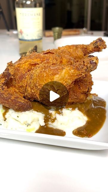 a white plate topped with meat covered in gravy next to a bottle of wine