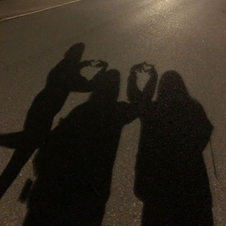 two people standing next to each other in the street with their shadow on the ground