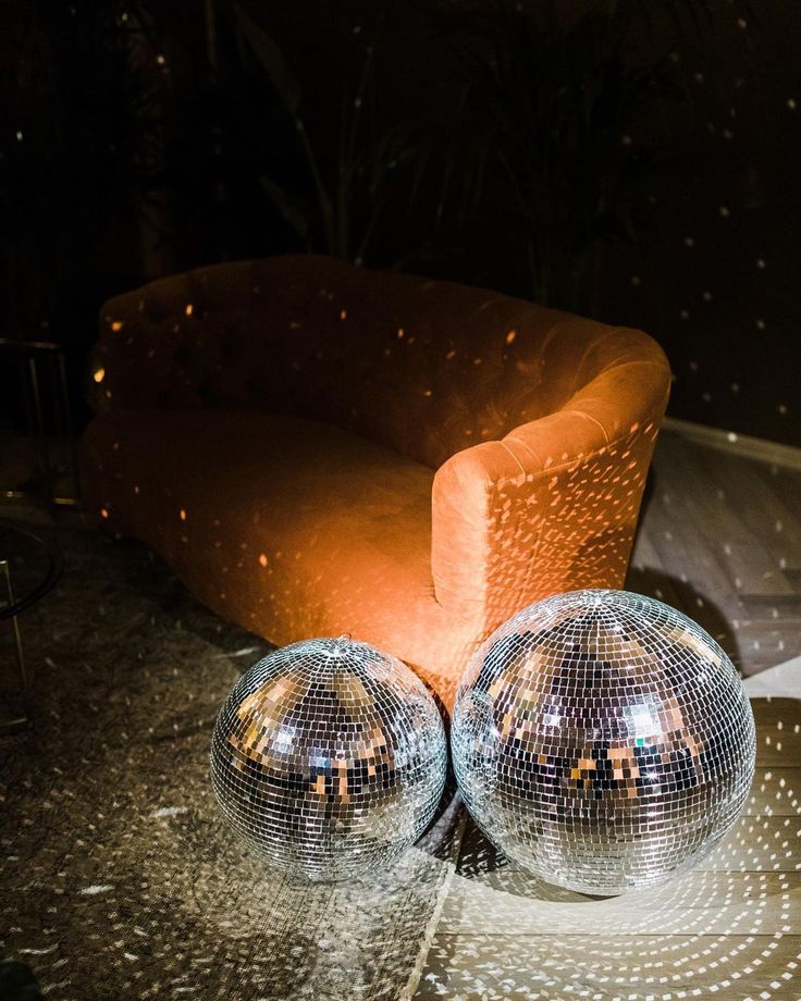 two shiny disco balls sitting on top of a table next to a couch and chair