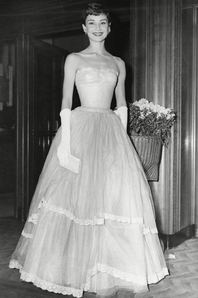 an old black and white photo of a woman in a dress with gloves on her hand