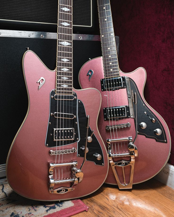 two pink guitars sitting next to each other