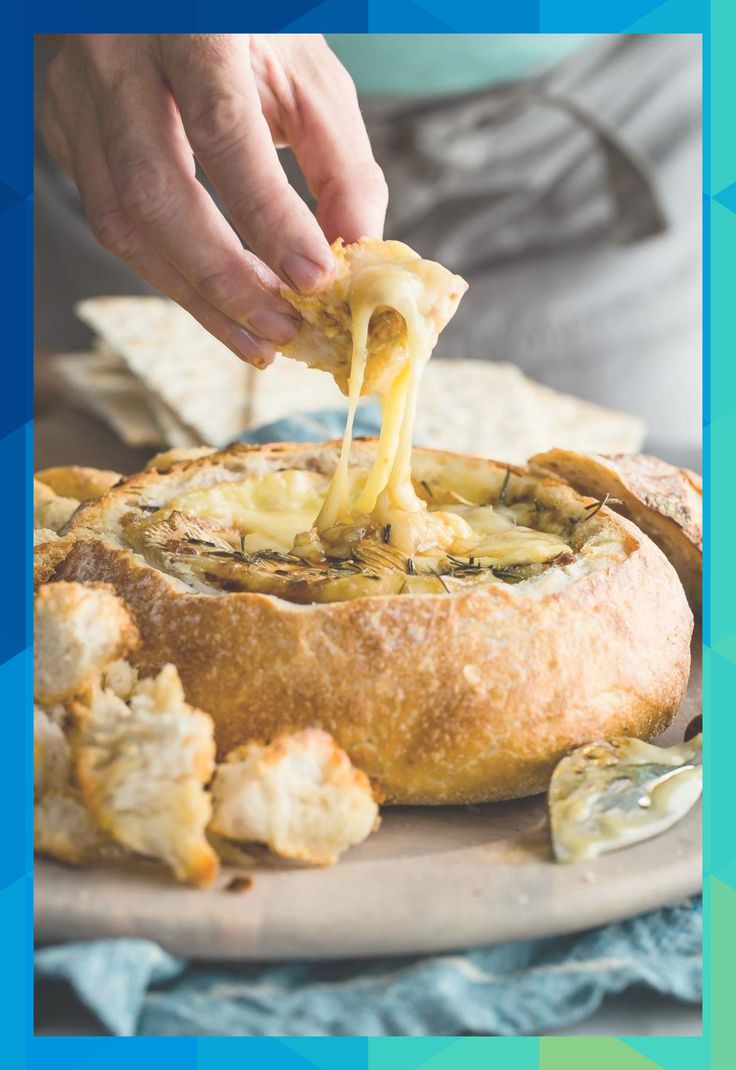 a person is dipping cheese into a bread dish