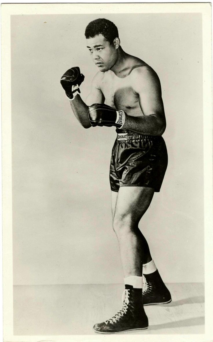 an old black and white photo of a man in boxing shorts with gloves on his hands