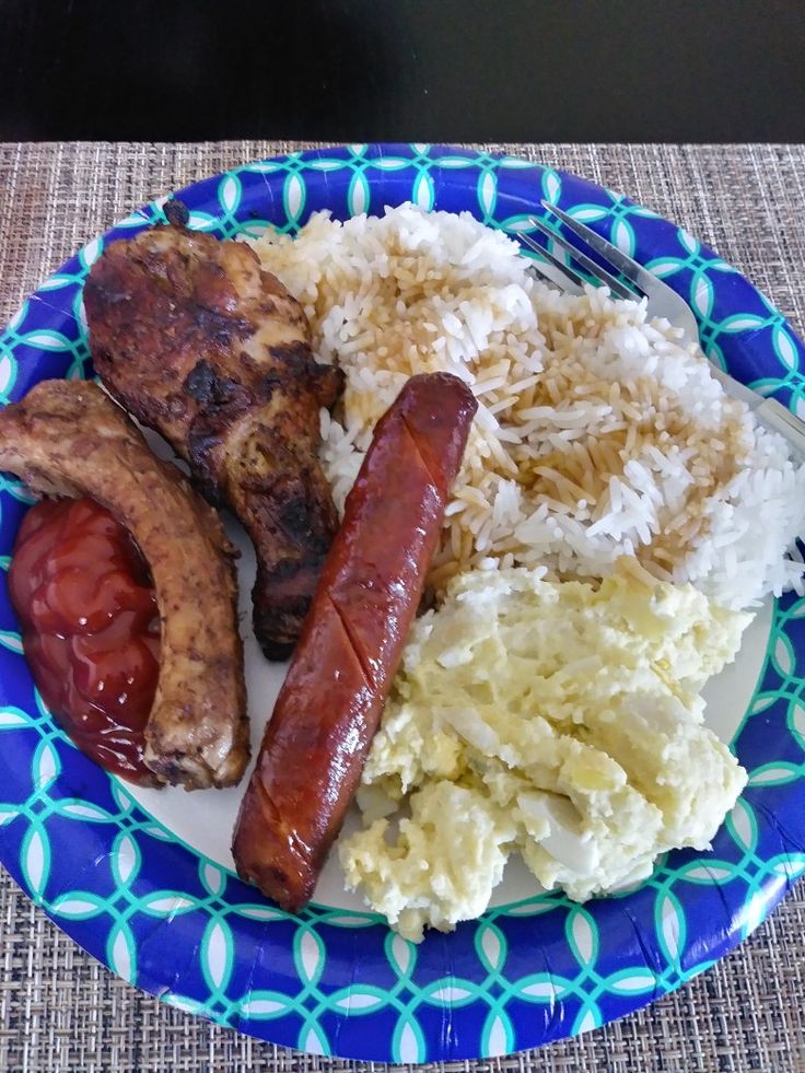 a blue and white plate topped with meat, rice and beans