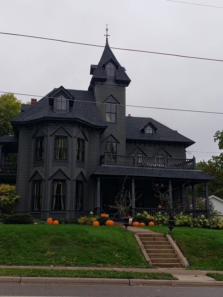 a large gray house sitting on top of a lush green field