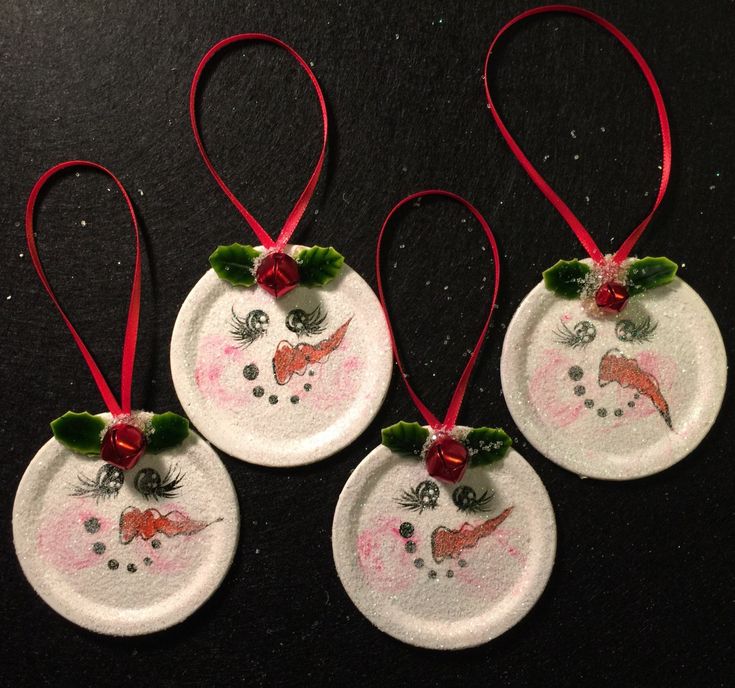 three snowman ornaments hanging from red ribbon