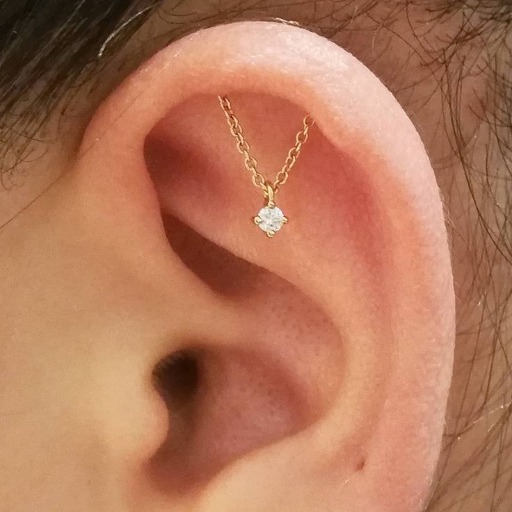 a close up of a person's ear with a chain attached to the back of it