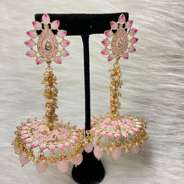 The exquisite and unique Baby Pink Nashira Jhumka are the perfect jhumkas for both party wear. This beautiful drop jhumka features dangling pearls, Baby Pink beads, Hand-painted Meenakari, and high-quality kundan on Gold-Plating. Specifications Materials used: Baby Pink Beads, Meenakari, pearls, gold plating Length: 10 cm Weight: 38 grams At Romikas, we pride ourselves on the craftsmanship and high quality of our jewelry, designed to enhance your natural beauty. Please contact us with any questi Temple Jewelry Jhumkas For Party, Temple Jewelry Style Jhumkas For Party, Temple Jewelry Style Party Jhumkas, Festive Bridal Earrings With Meenakari, Peacock Design Danglers For Celebrations And Festivals, Festival Celebration Peacock Design Danglers, Temple Jewelry Style Jhumkas With Latkans For Party, Traditional Peacock Design Danglers For Party, Traditional Peacock Danglers For Party