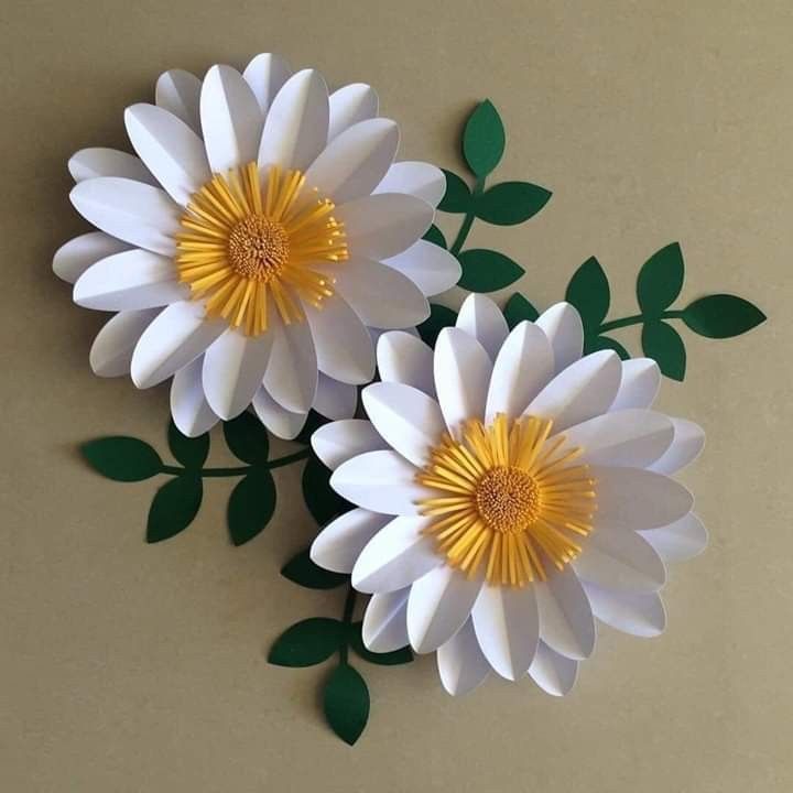 three paper flowers with green leaves on the top and one white flower in the middle