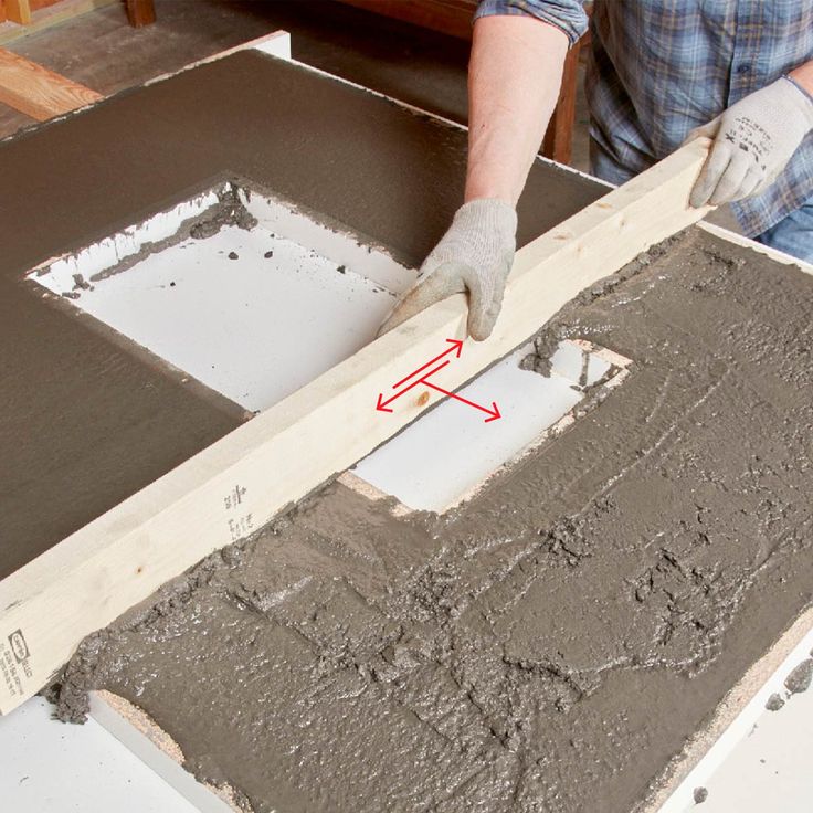 a man is working with cement on the floor in front of a table that's being built