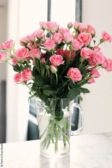 a vase filled with pink roses sitting on top of a table