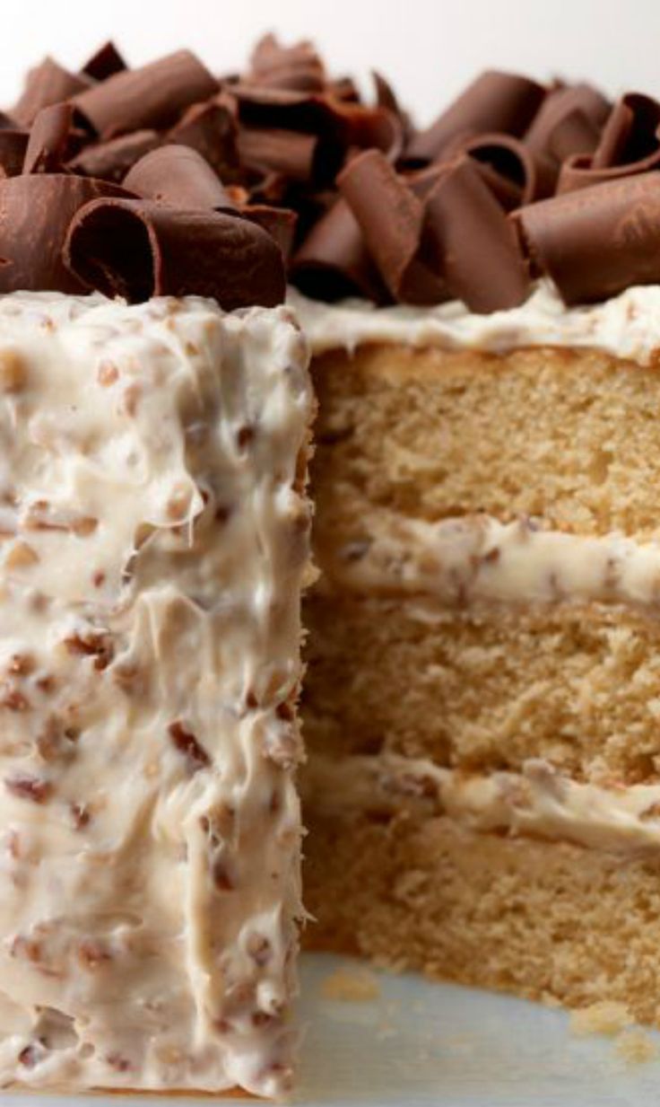 a close up of a slice of cake with frosting and chocolate chips on top