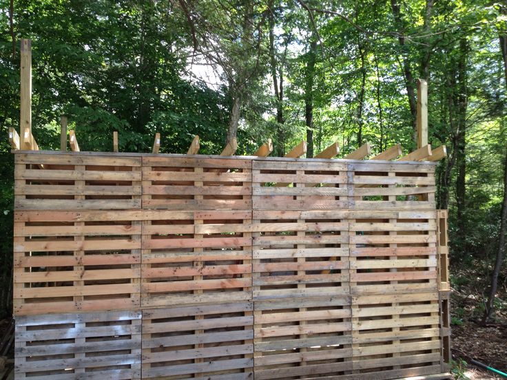 several wooden pallets stacked on top of each other in front of trees and bushes