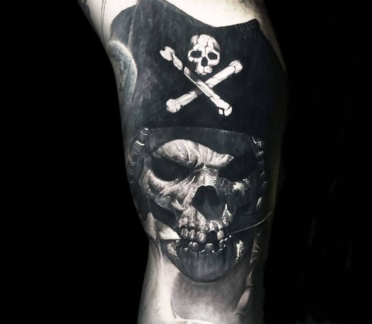 a man with a skull and crossbones tattoo on his leg is wearing a pirate hat