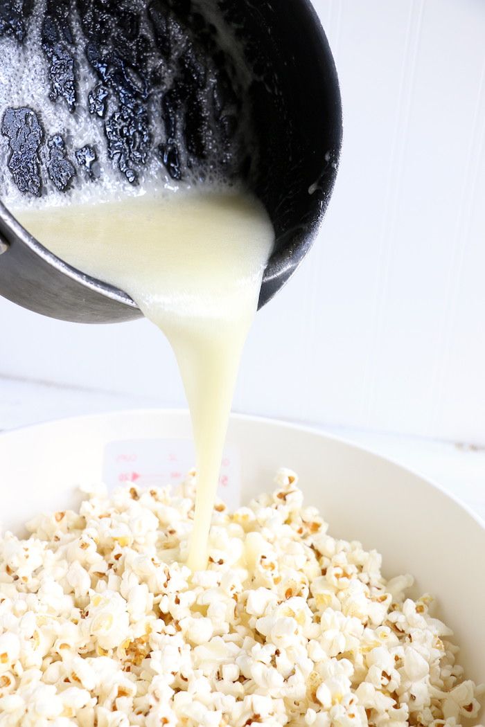 a white bowl filled with popcorn and milk being poured into it's side dish