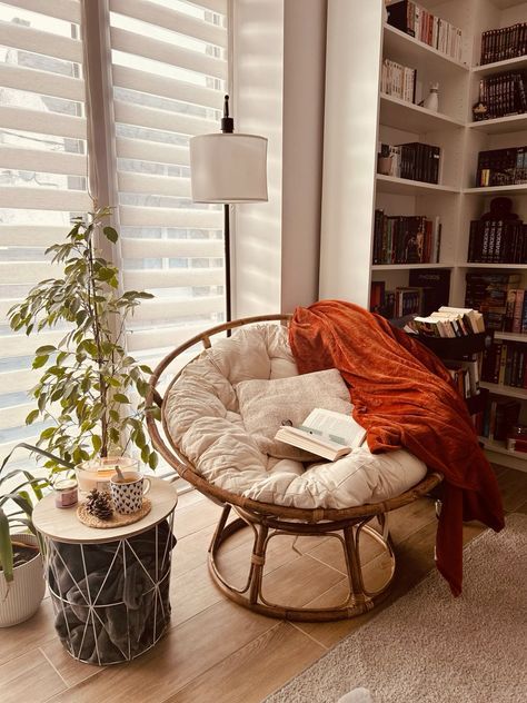 a chair with a blanket on it in front of a book shelf filled with books