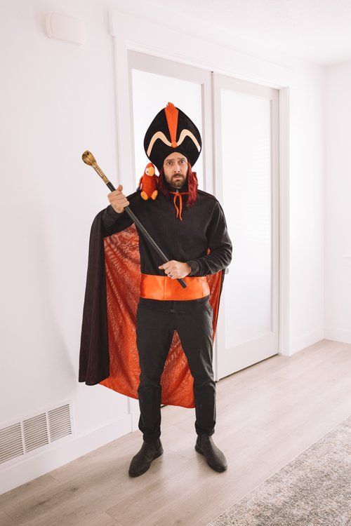 a man dressed in an orange and black costume holding a baseball bat while standing on a hard wood floor