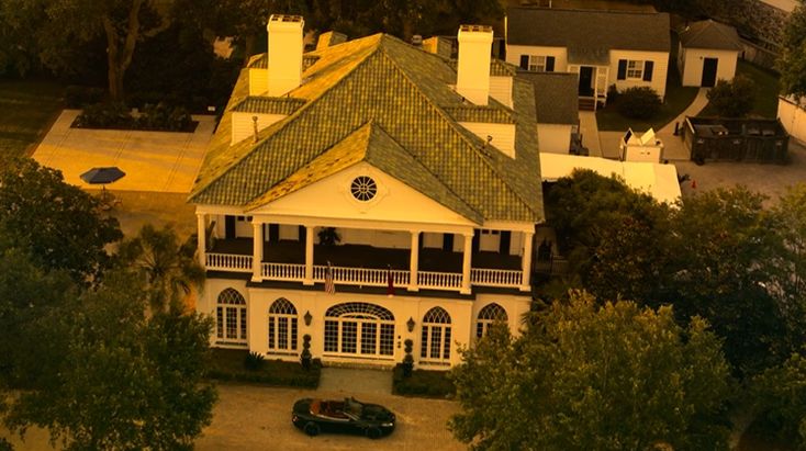 an aerial view of a house with cars parked in the driveway and trees surrounding it