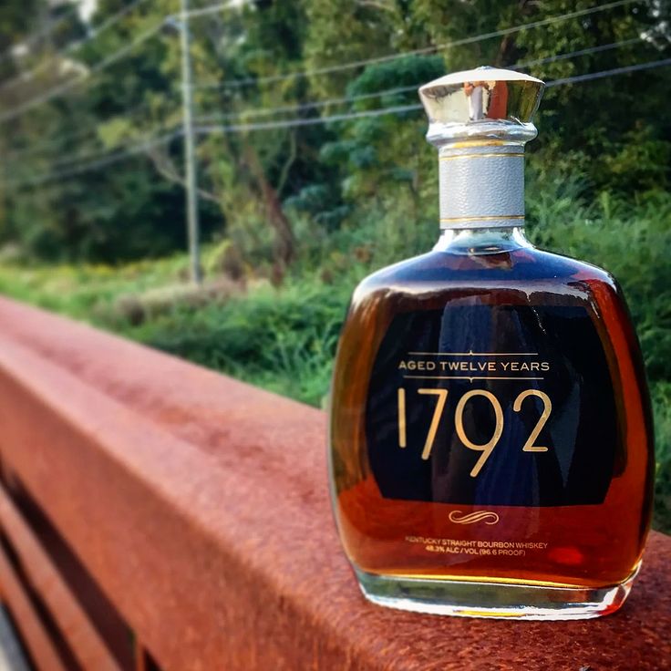 a bottle of whiskey sitting on top of a wooden bench