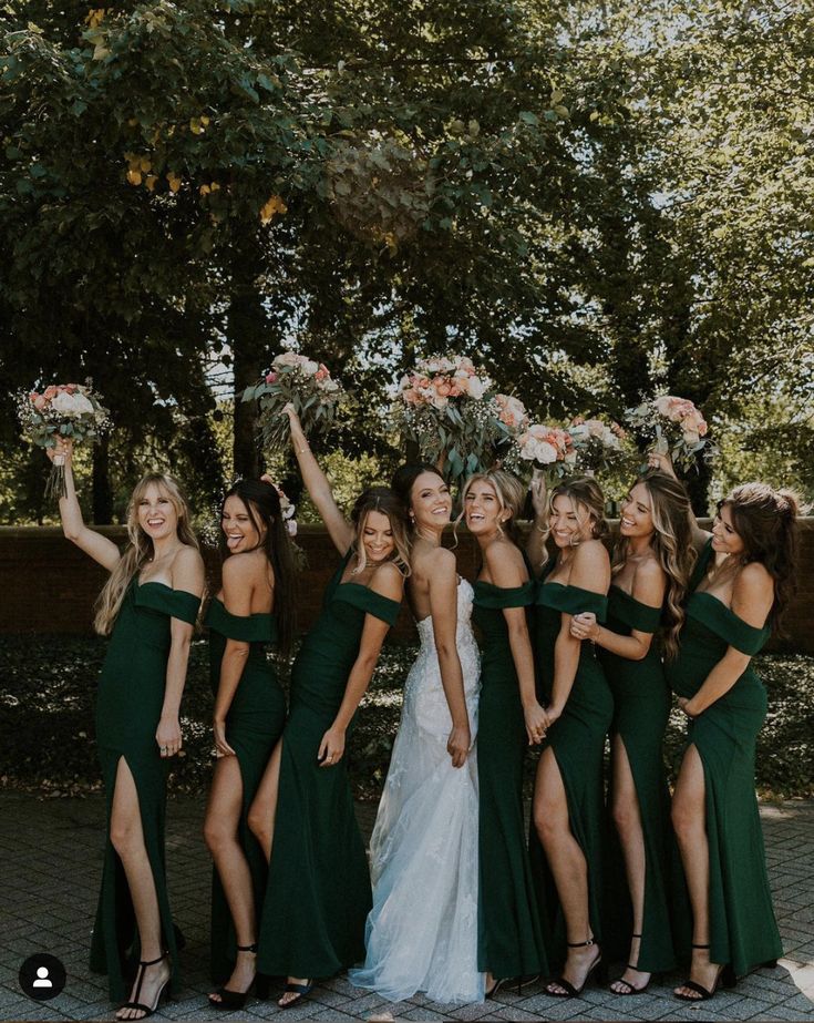 a group of women in green dresses standing next to each other with their arms in the air