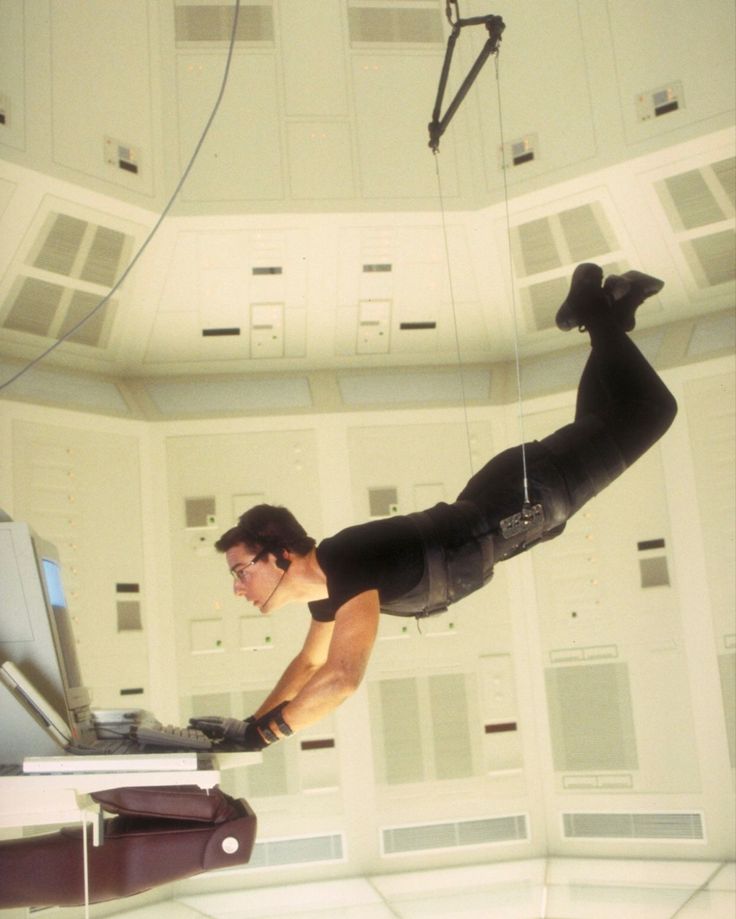 a man flying through the air while riding on top of a laptop computer next to another person