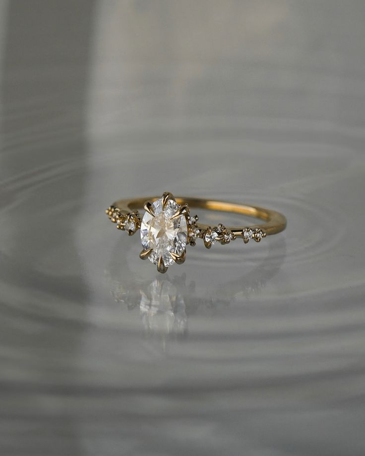 a close up of a diamond ring on a surface with water ripples around it